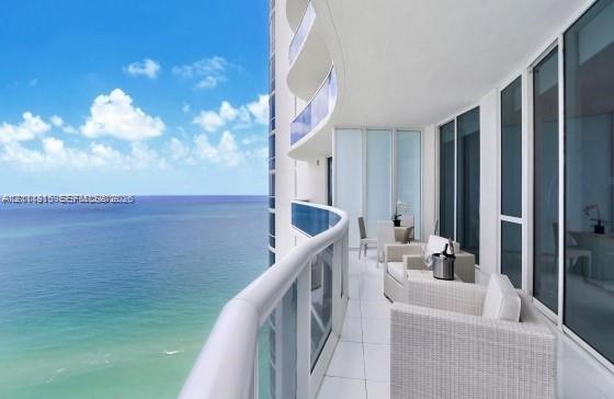 Expansive curved balcony featuring floor-to-ceiling glass railings, large-format tile flooring, and full-height glass sliding door access Expansive curved balcony featuring floor-to-ceiling glass railings, large-format tile flooring, and full-height glass sliding door access