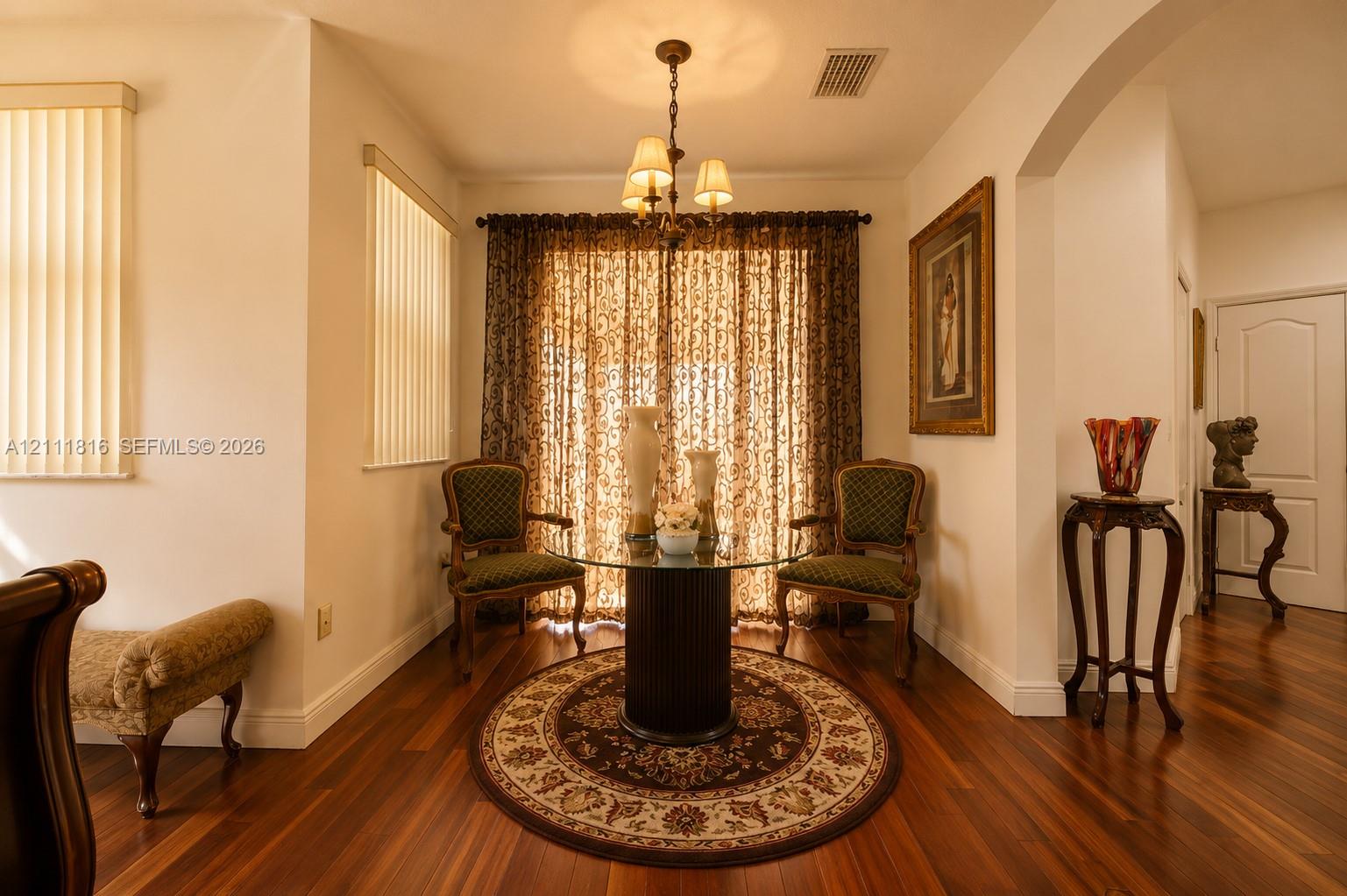Interior space featuring wood-finish flooring, a multi-light chandelier, and an arched entryway