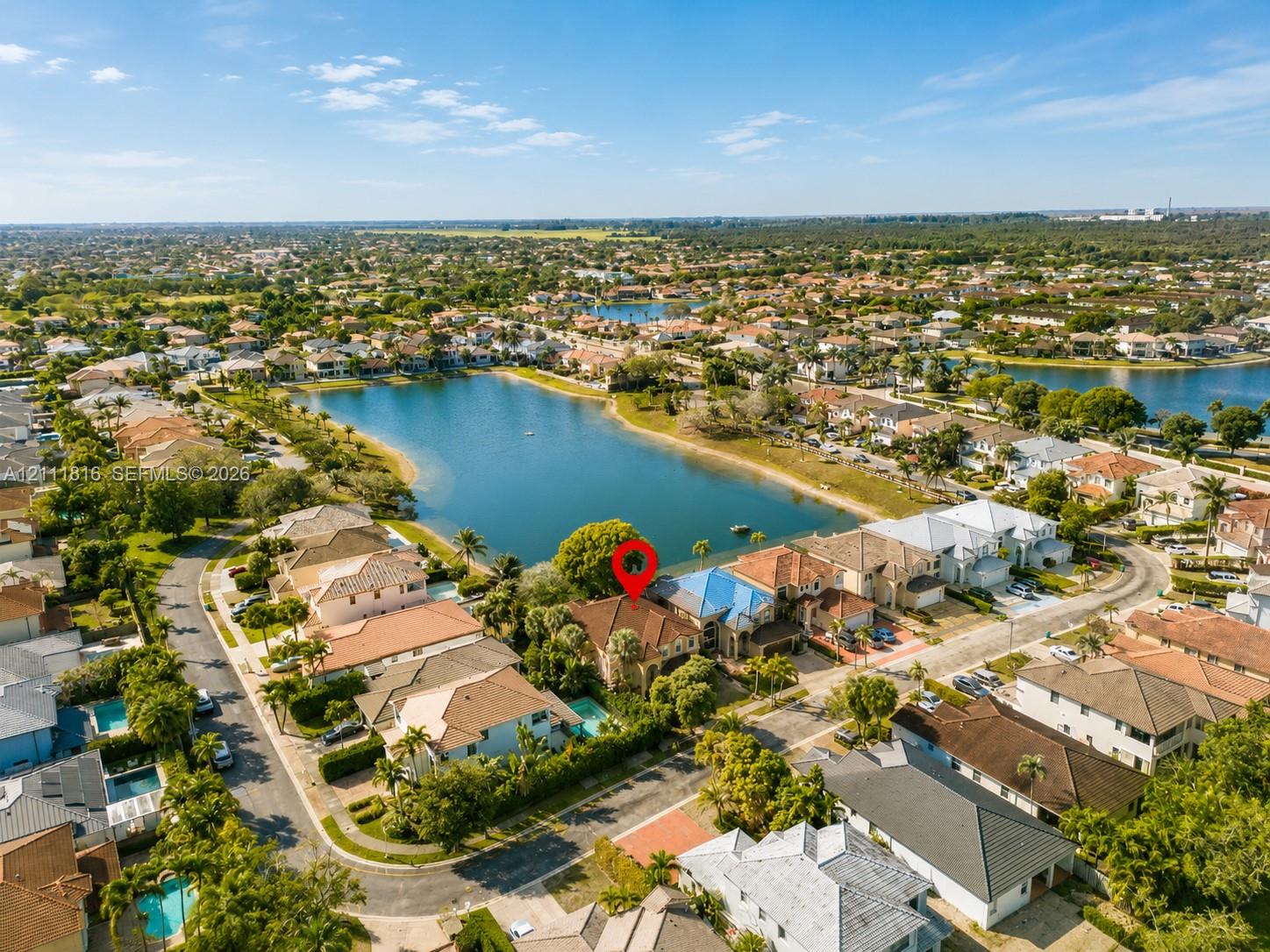 Aerial perspective of a multi-story residence featuring a tile roof, a private swimming pool, and direct proximity to a central lake
