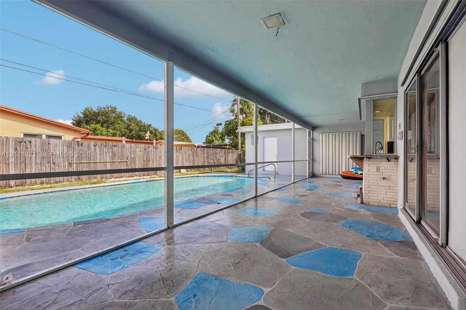 Screened-in lanai featuring a stamped concrete floor, built-in masonry bar, and a private swimming pool