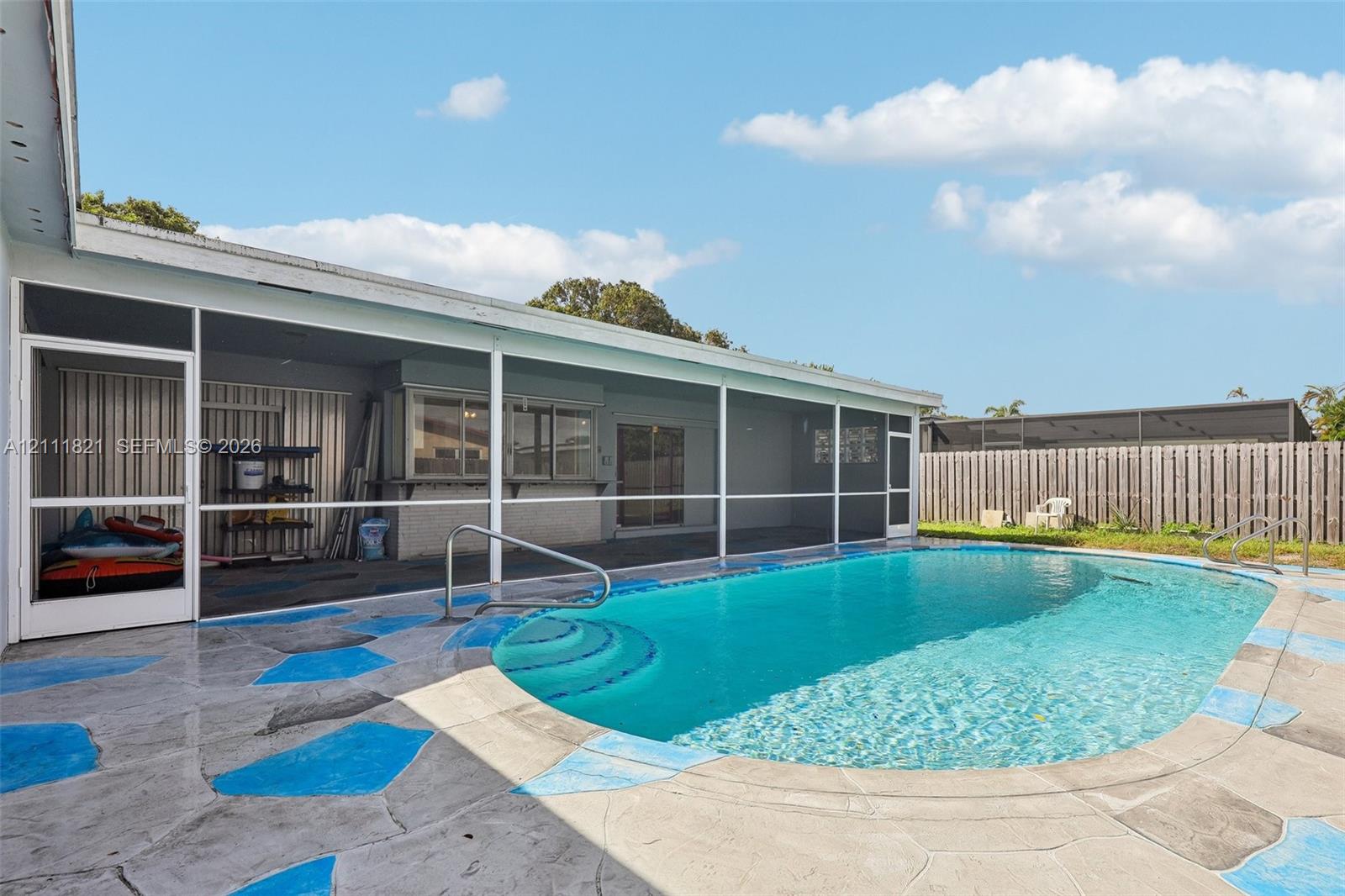 Screened-in patio featuring a concrete pool deck, in-ground swimming pool with steps, and full-perimeter privacy fencing