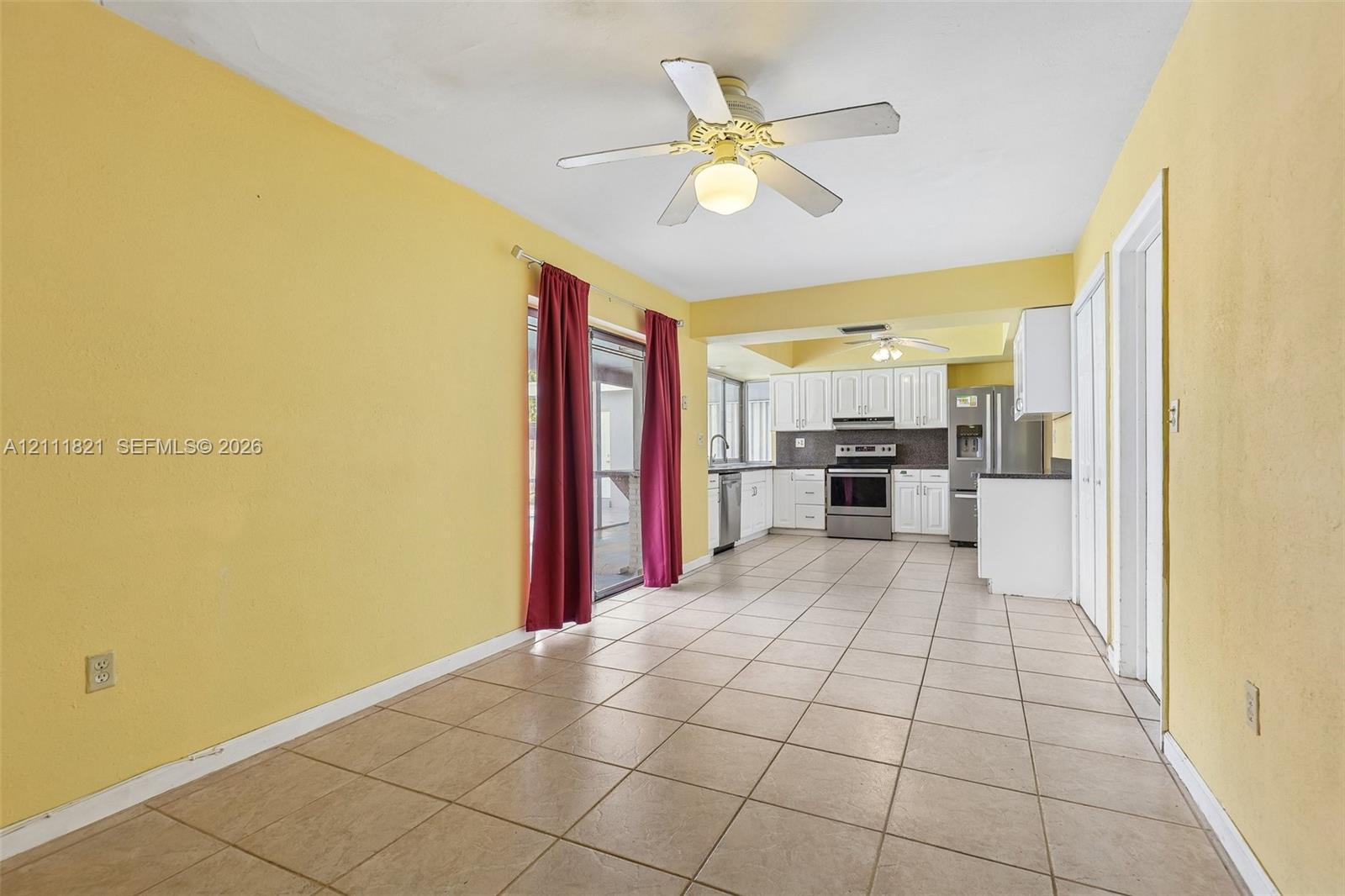 Ceramic tile flooring, white shaker-style cabinetry, stainless steel kitchen appliances, and ceiling-mounted fans