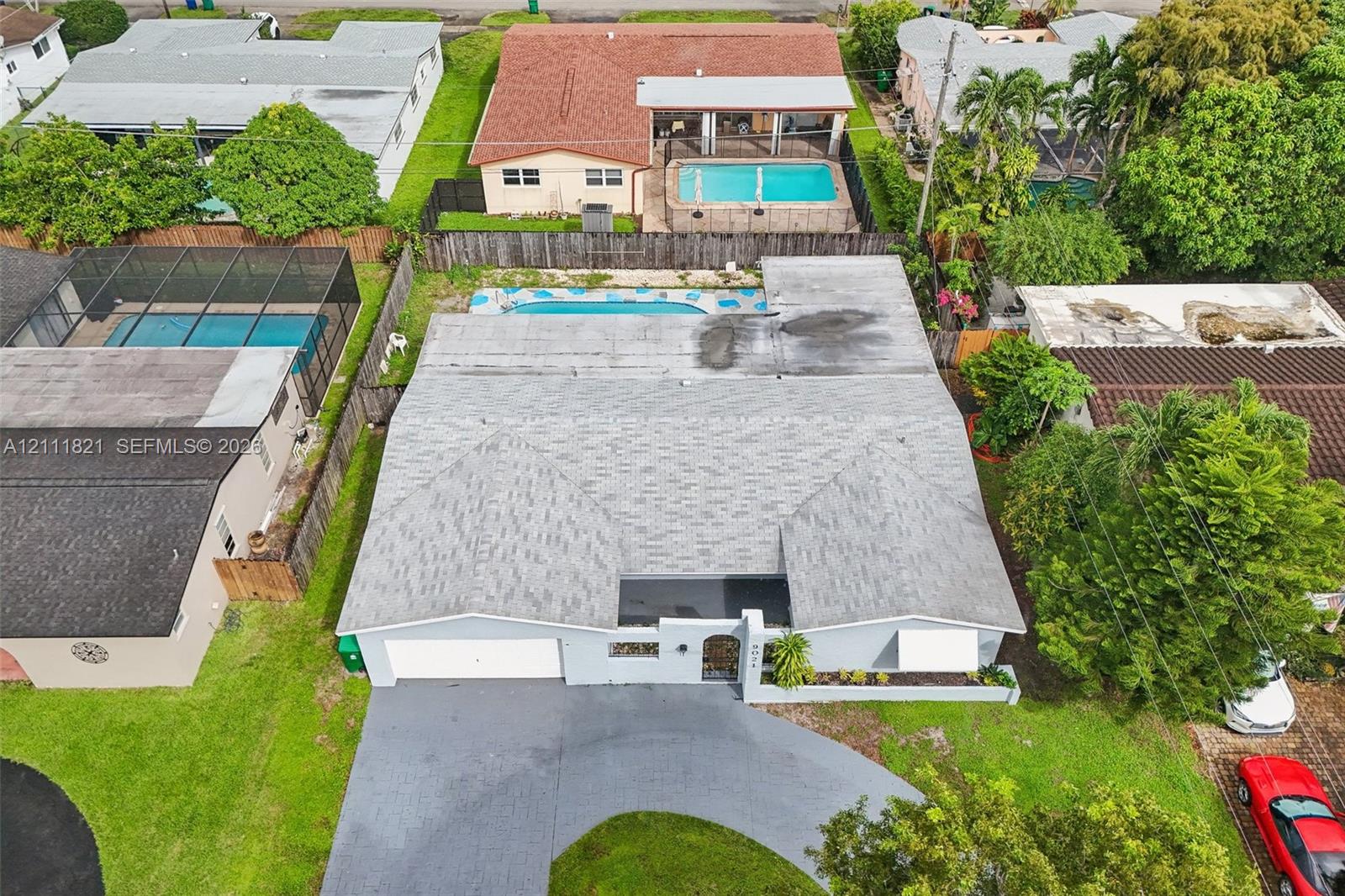 Aerial perspective of a single-story residence featuring an asphalt shingle roof, a two-car garage, a concrete driveway, and an in-ground swimming pool