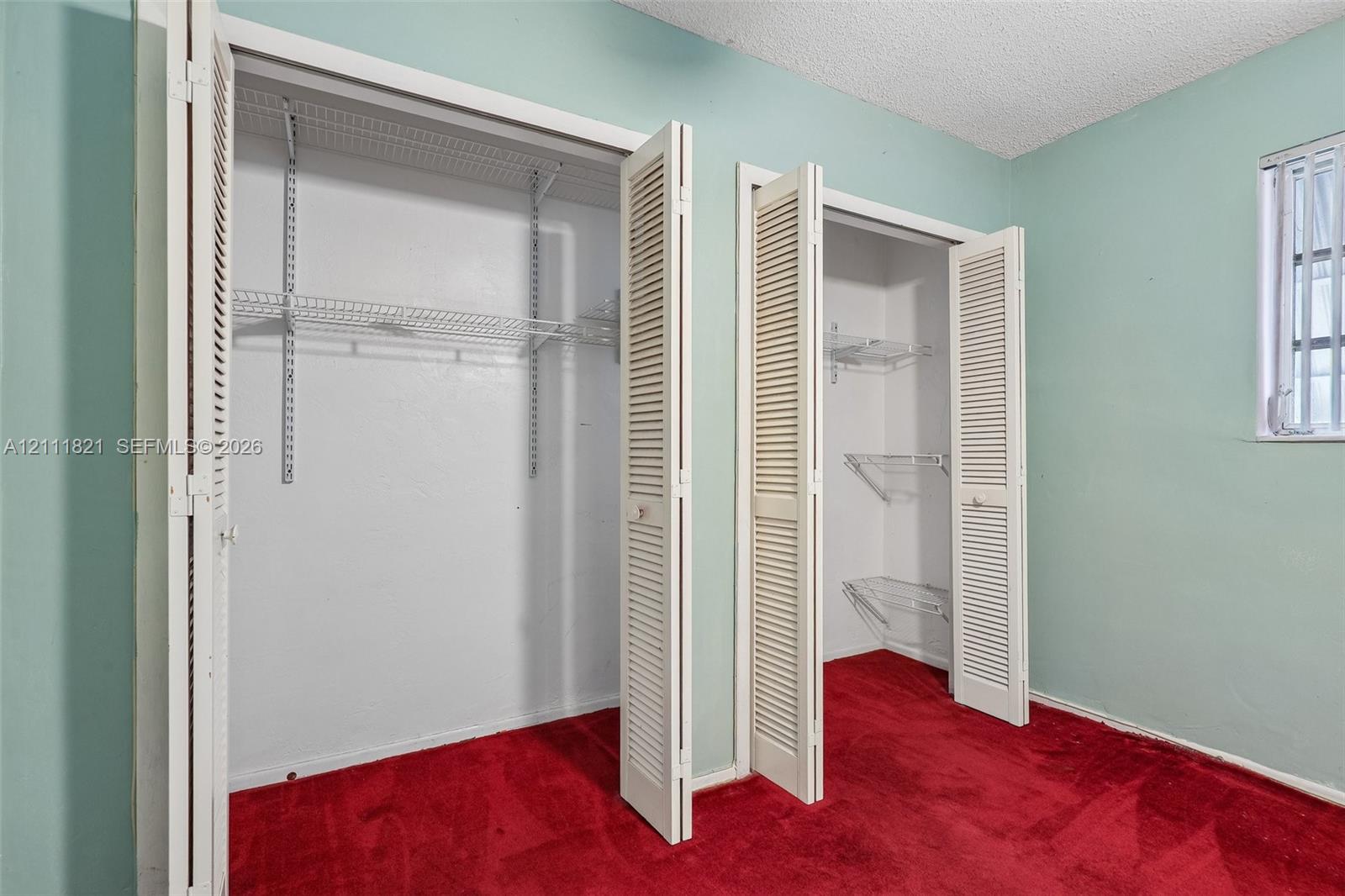 Dual closets featuring white louvered bifold doors, adjustable wire shelving, and wall-to-wall carpeting