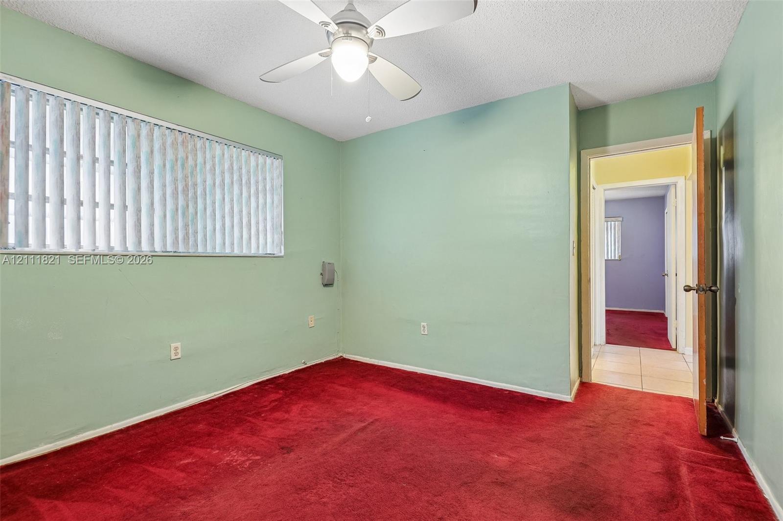 Room featuring wall-to-wall carpeting, a ceiling-mounted light fixture with fan, and horizontal window blinds