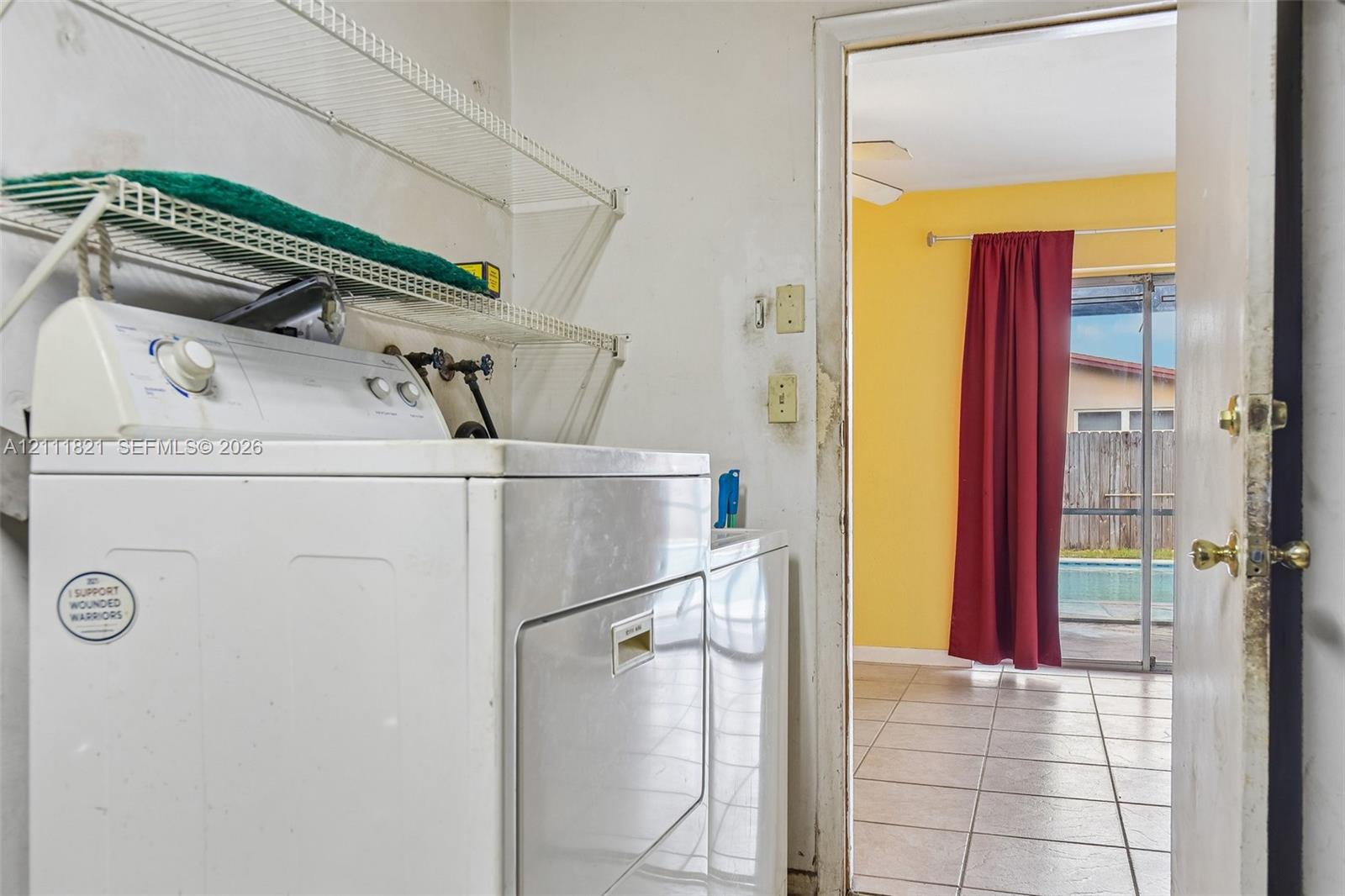 Utility area featuring white wire wall-mounted shelving and tile flooring