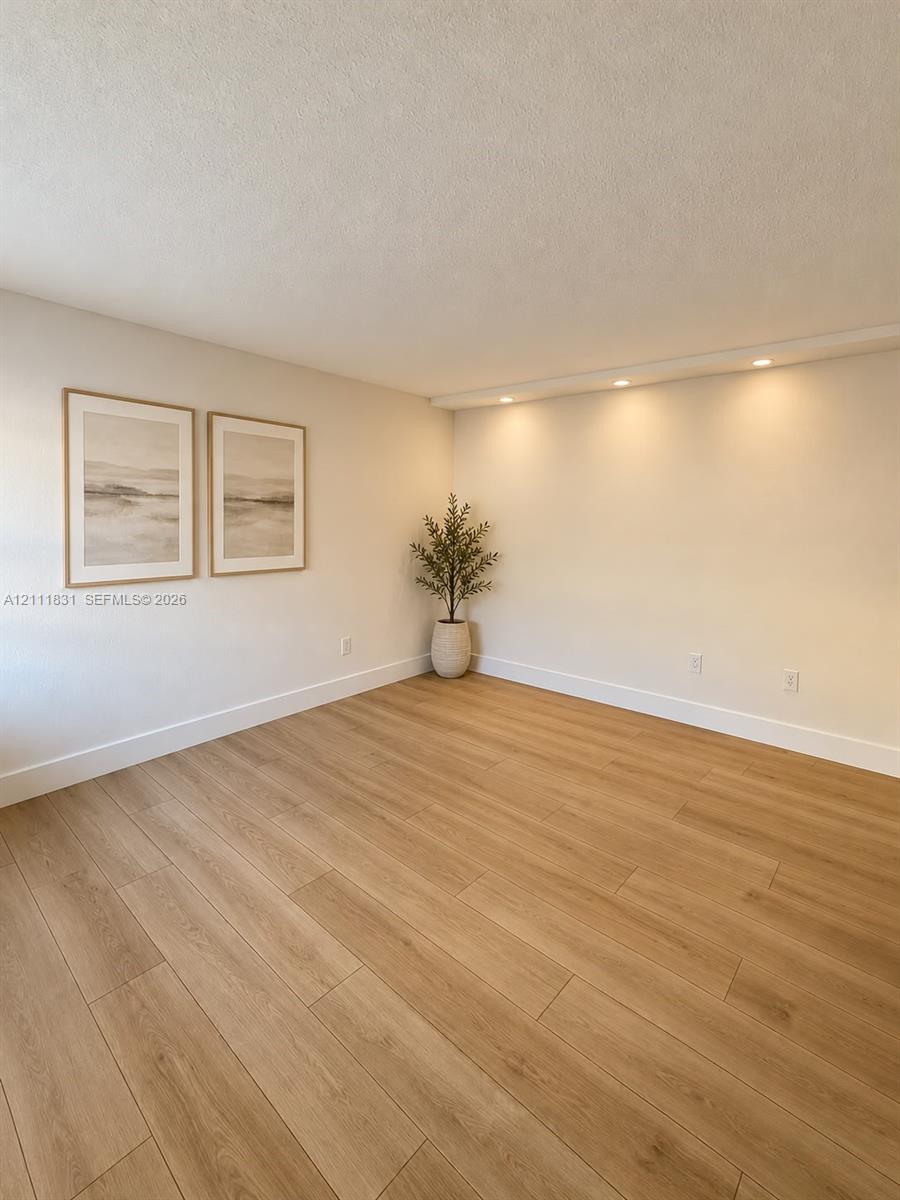 Neutral-toned room featuring wood-finish flooring and recessed ceiling lighting