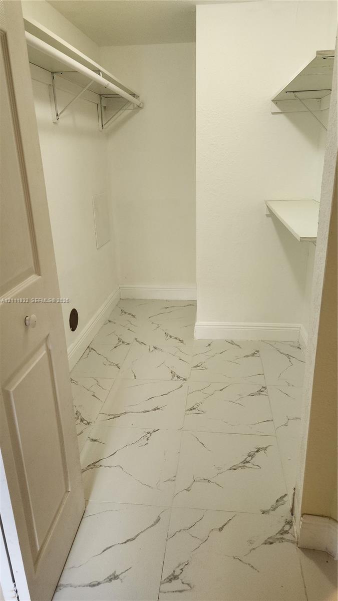 Walk-in closet featuring stone-finish floor tiling and multi-level built-in shelving