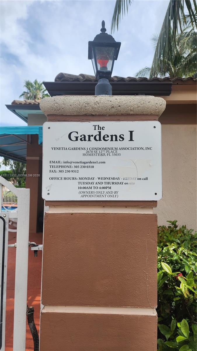 Stucco-finished masonry pillar featuring an attached lantern-style lighting fixture