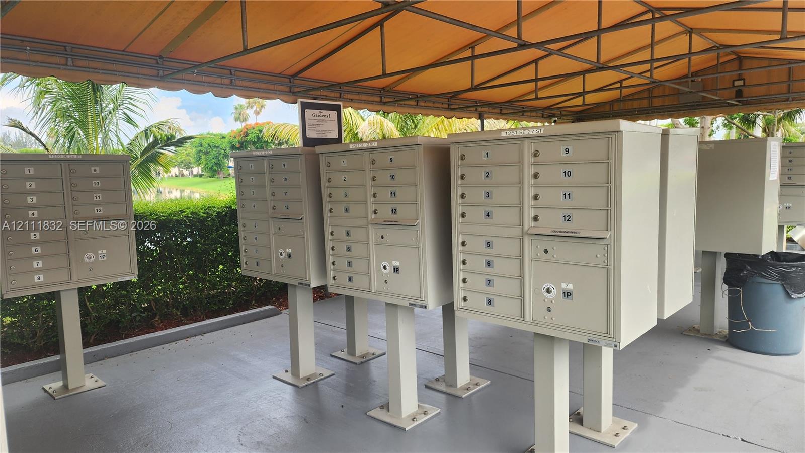 Centralized cluster mailbox station featuring metal pedestal-mounted compartments and a protective overhead canopy