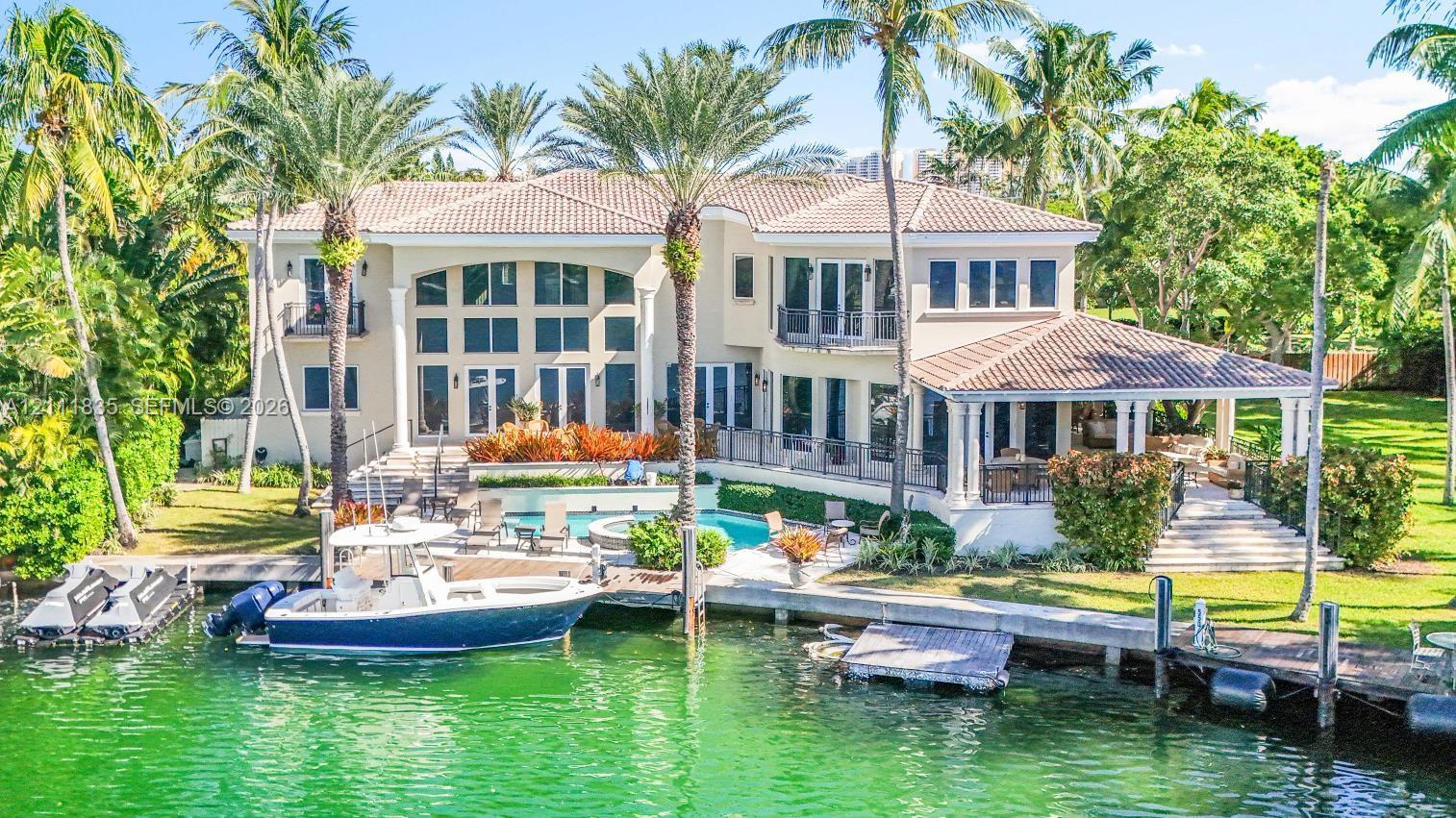 Two-story waterfront residence featuring a tile roof, private boat dock, swimming pool with integrated spa, and covered terrace Two-story waterfront residence featuring a tile roof, private boat dock, swimming pool with integrated spa, and covered terrace