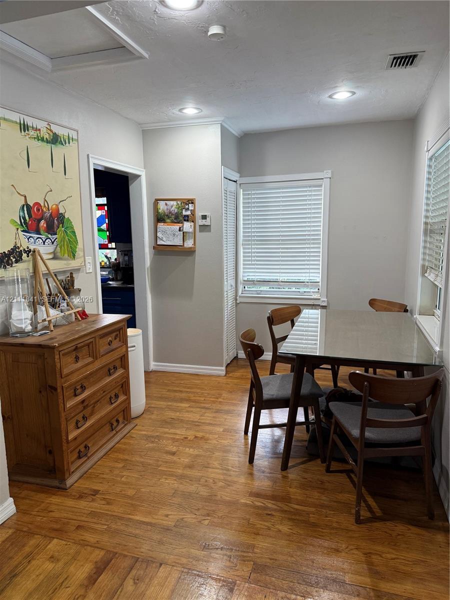 Wood-finish flooring, recessed lighting, neutral wall paint, white louvered-door closet, and dual windows with horizontal blinds