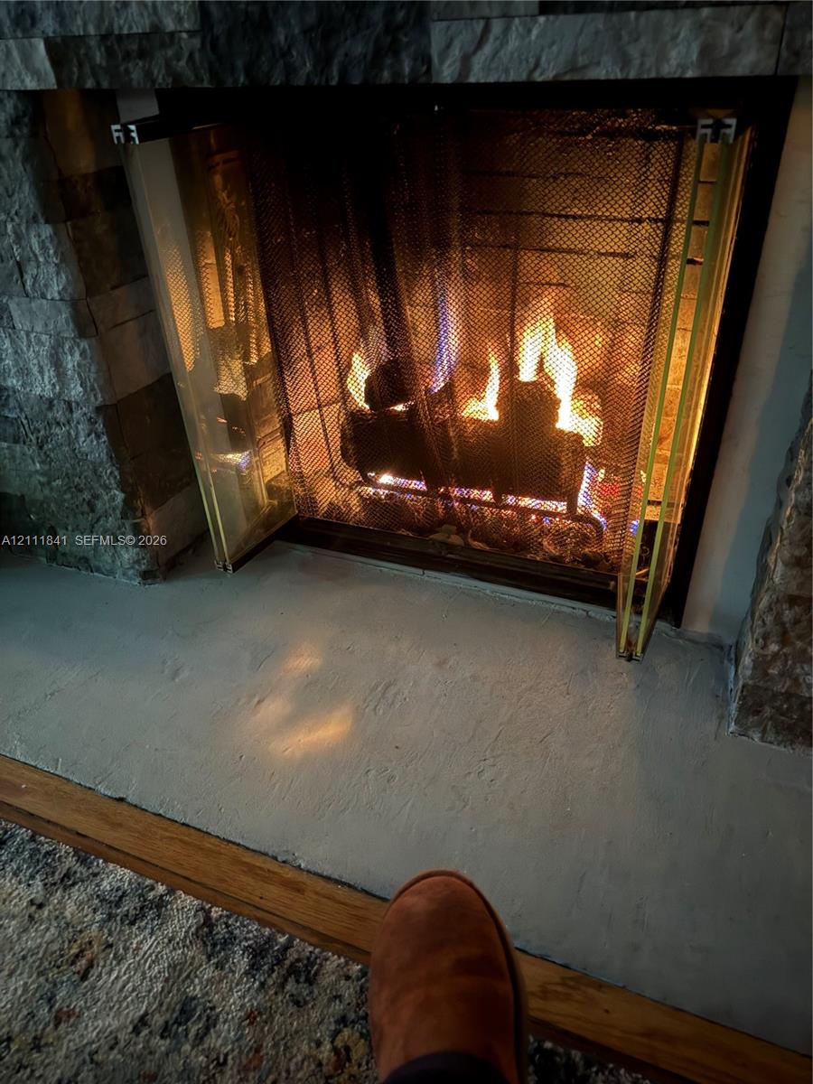 Fireplace featuring a multi-tonal stacked stone surround, metal mesh screen, and a solid hearth