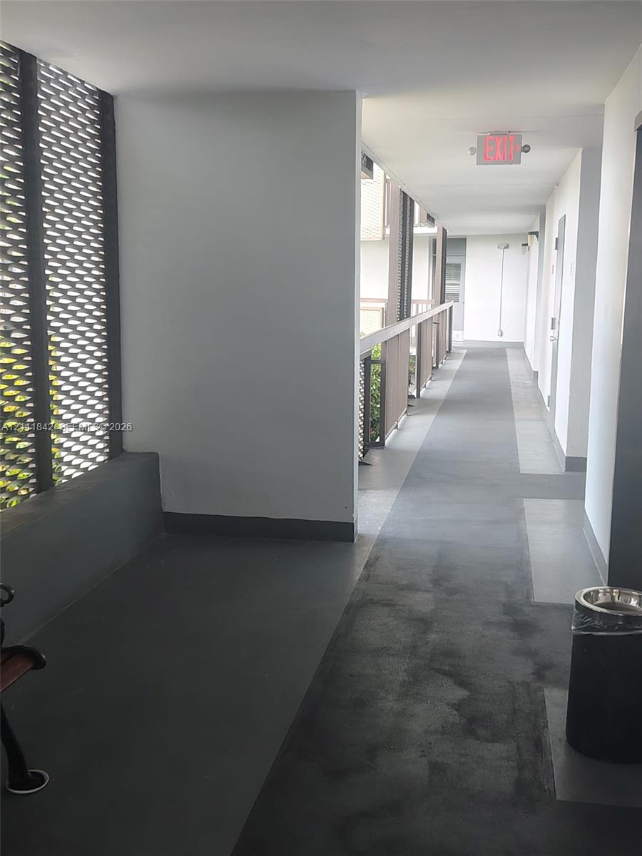 Covered exterior corridor featuring painted concrete flooring and decorative metallic lattice privacy screening