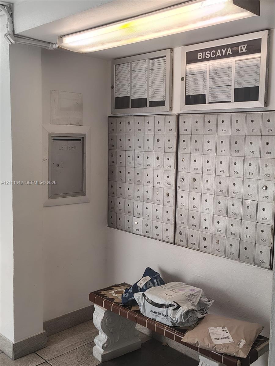 Secured metal mail distribution center featuring a built-in mail slot and overhead fluorescent lighting