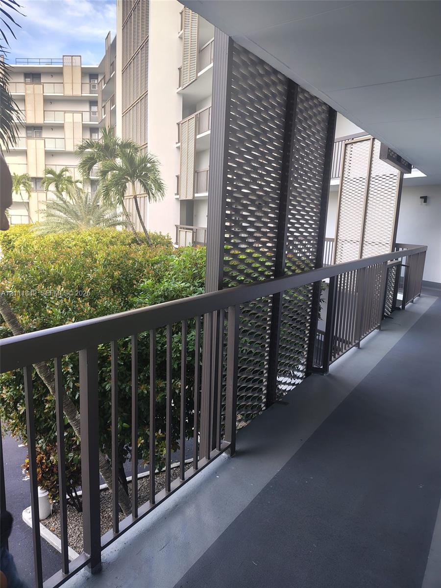 Covered exterior walkway featuring a metal railing and decorative perforated privacy screening