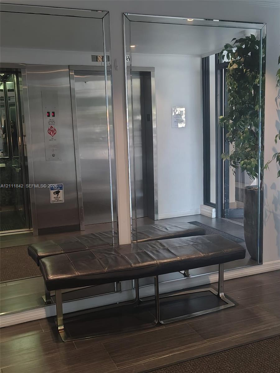 Full-height wall mirrors, stainless steel elevator doors, and wood-finish flooring