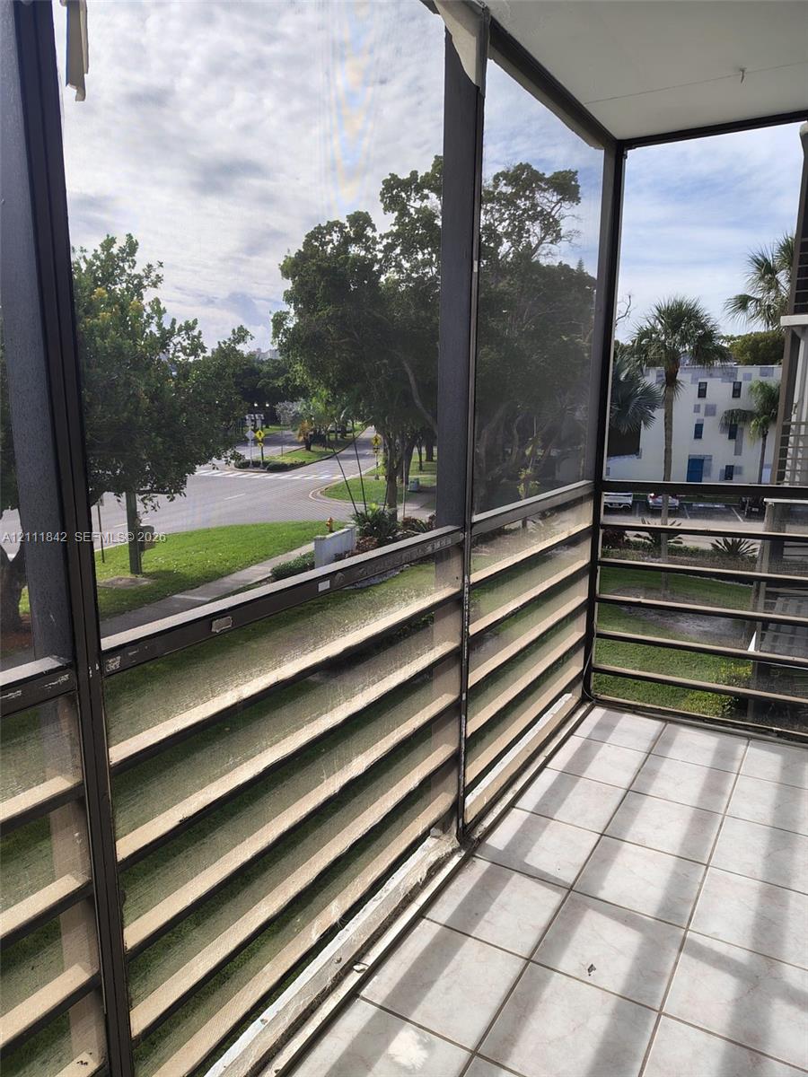Screened-in balcony featuring ceramic tile flooring, horizontal metal railings, and a metal frame enclosure