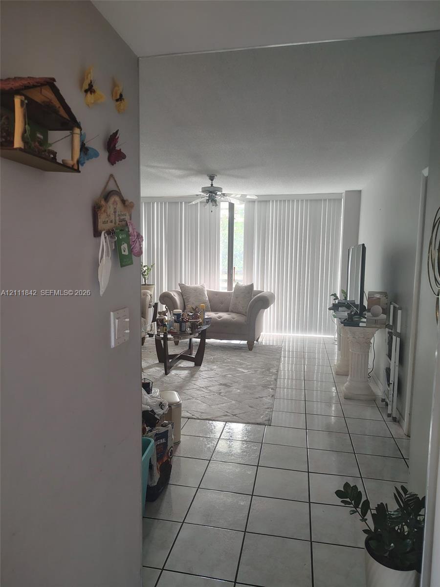 Interior space featuring tile flooring, ceiling fan, and floor-to-ceiling vertical blinds