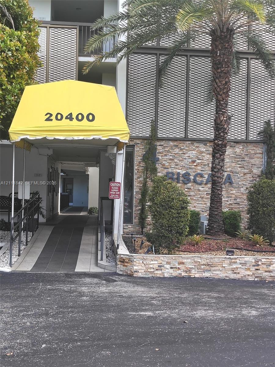Building exterior featuring stone masonry facade, decorative metal screening, concrete access ramp, and metal awning