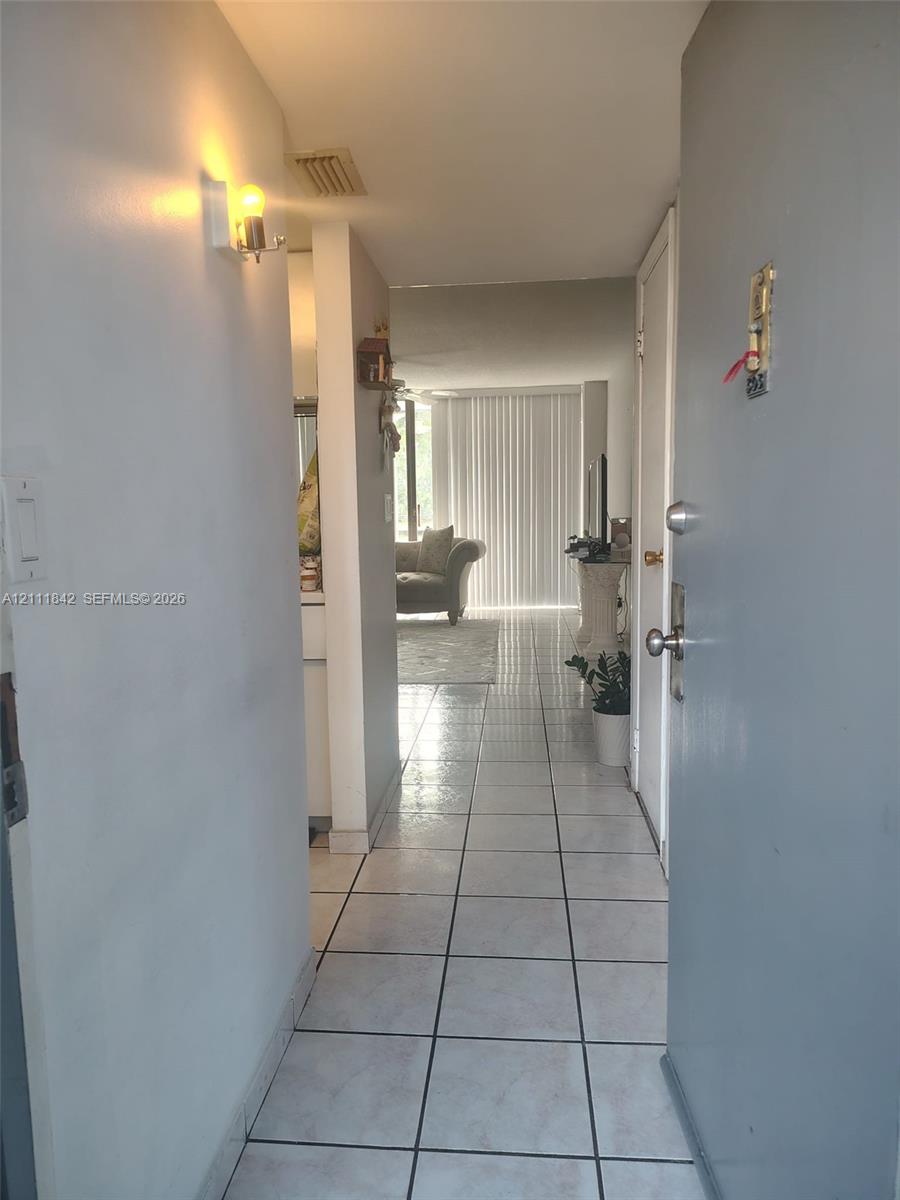 Entryway featuring neutral-toned tile flooring, wall-mounted sconce lighting, and white interior doors