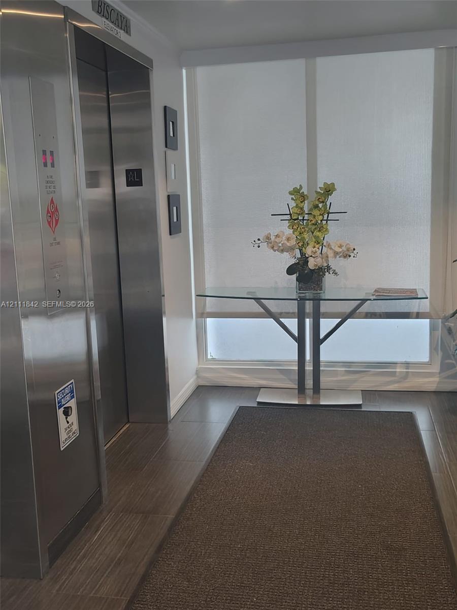 Stainless steel elevator with digital interface, floor-to-ceiling windows with integrated roller shades, and large-format tile flooring