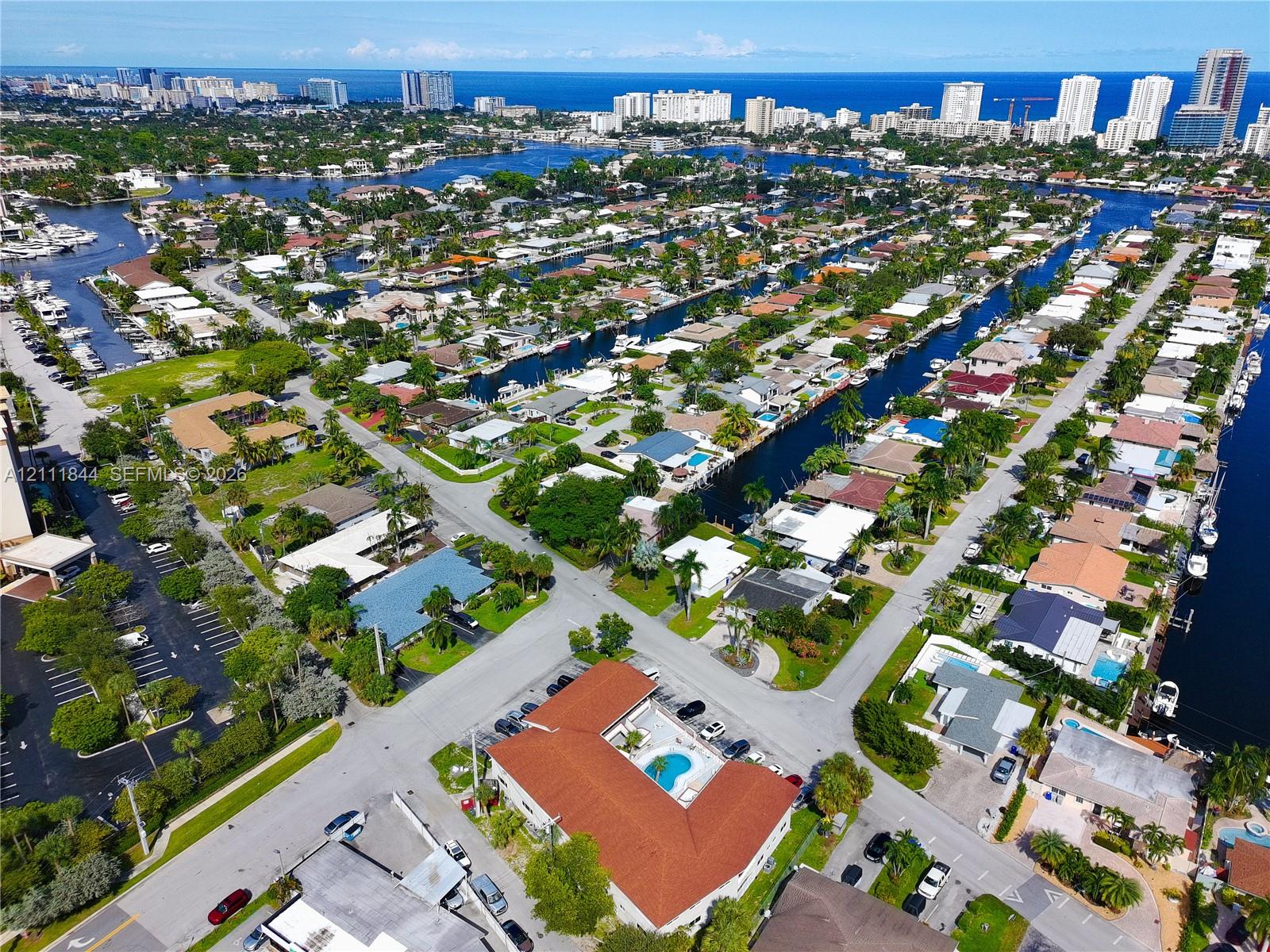 Aerial perspective featuring coastal waterway access, proximity to oceanfront skylines, expansive residential canal network, and established tropical landscaping