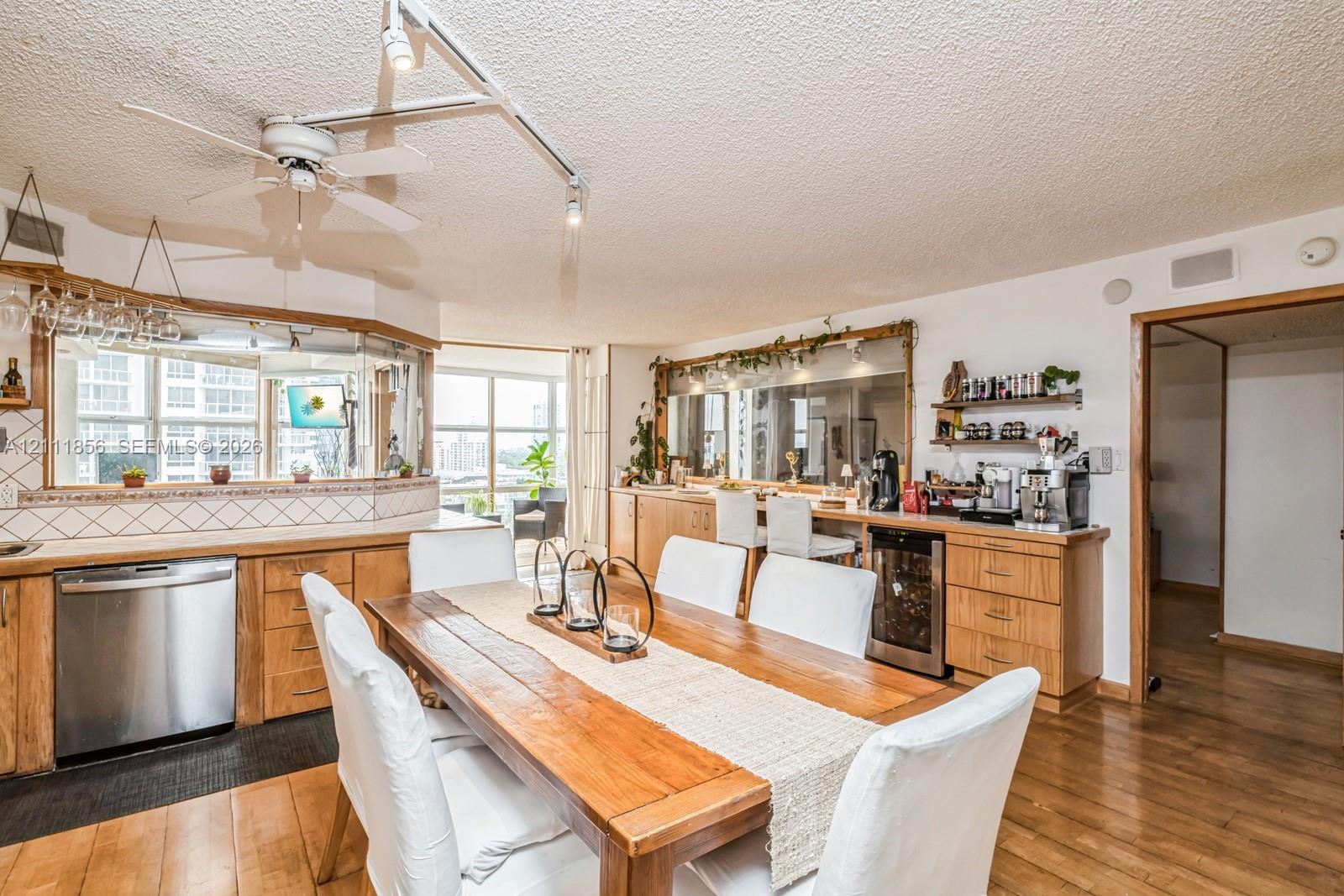 Kitchen featuring light-finish cabinetry, built-in wine refrigerator, stainless steel dishwasher, track lighting, and wood-finish flooring