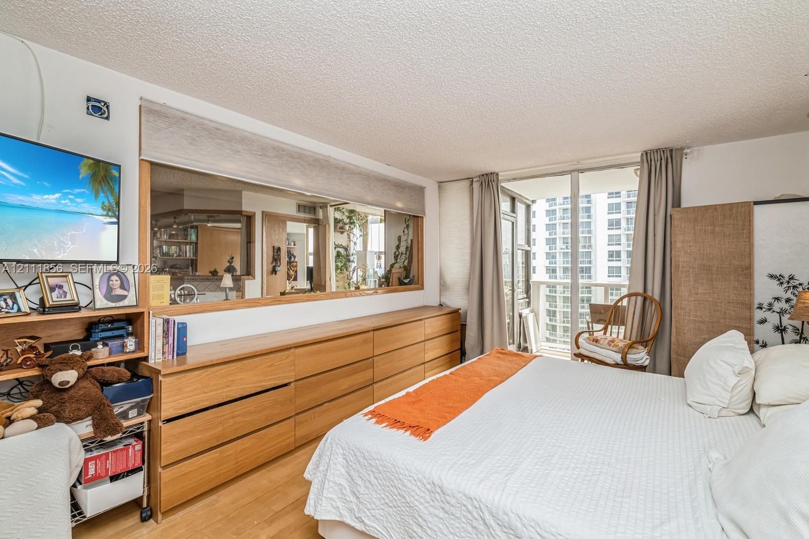 Wood-finish flooring, built-in wooden cabinetry, expansive wall mirror, and floor-to-ceiling glass door providing outdoor access