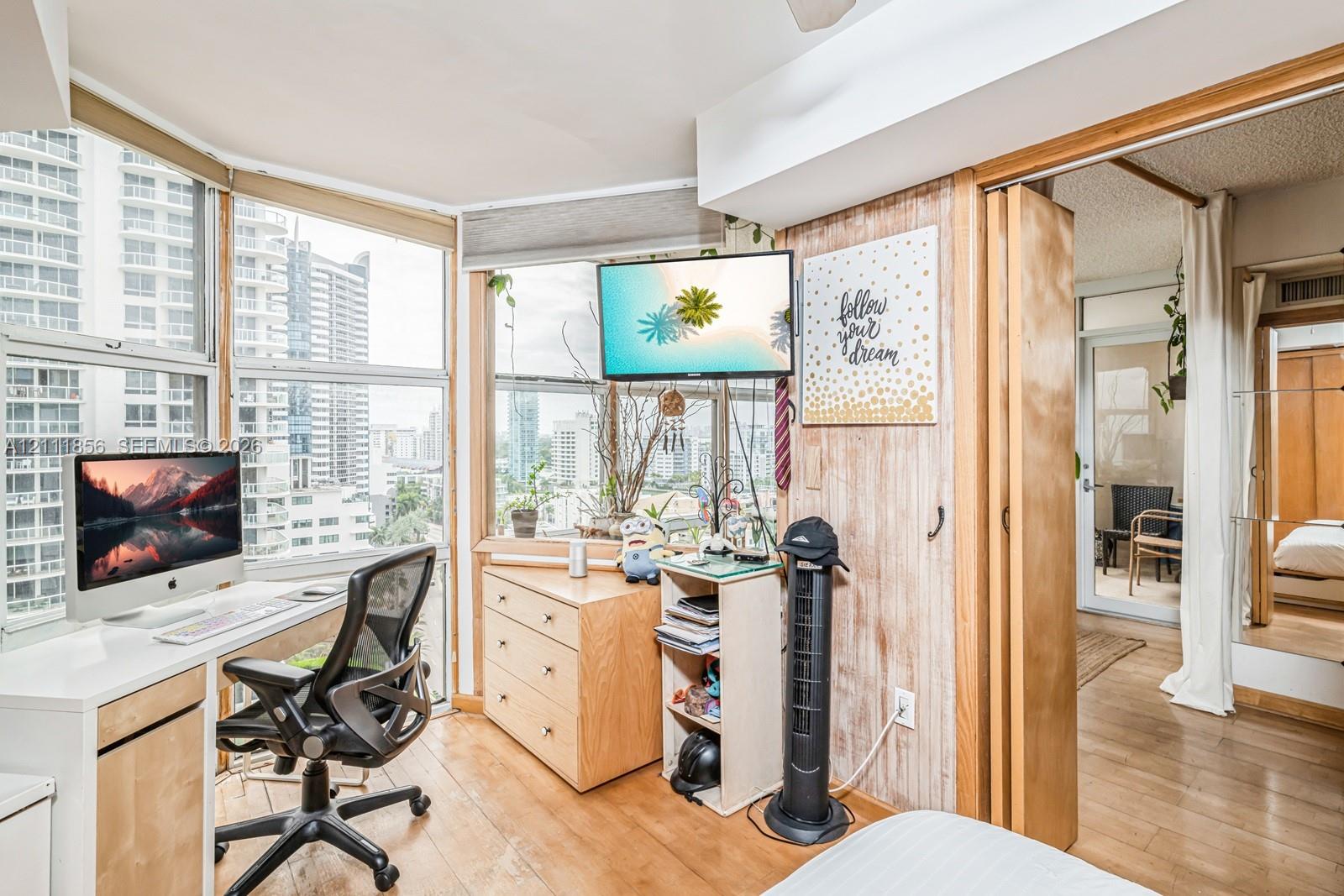 Floor-to-ceiling windows with urban exposure, wood-finish flooring, and wood-paneled accent wall