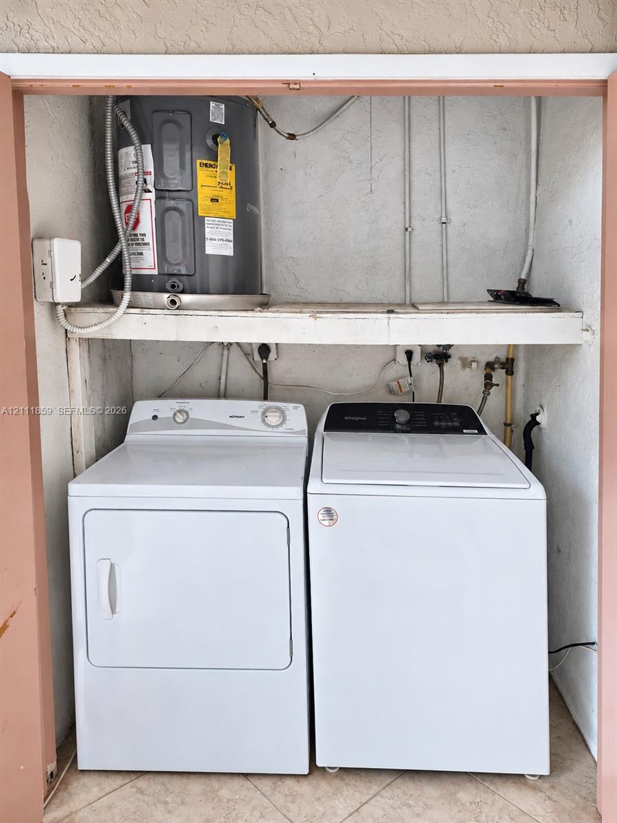 Dedicated laundry closet featuring a side-by-side washer and dryer, built-in overhead shelving, and an integrated water heater