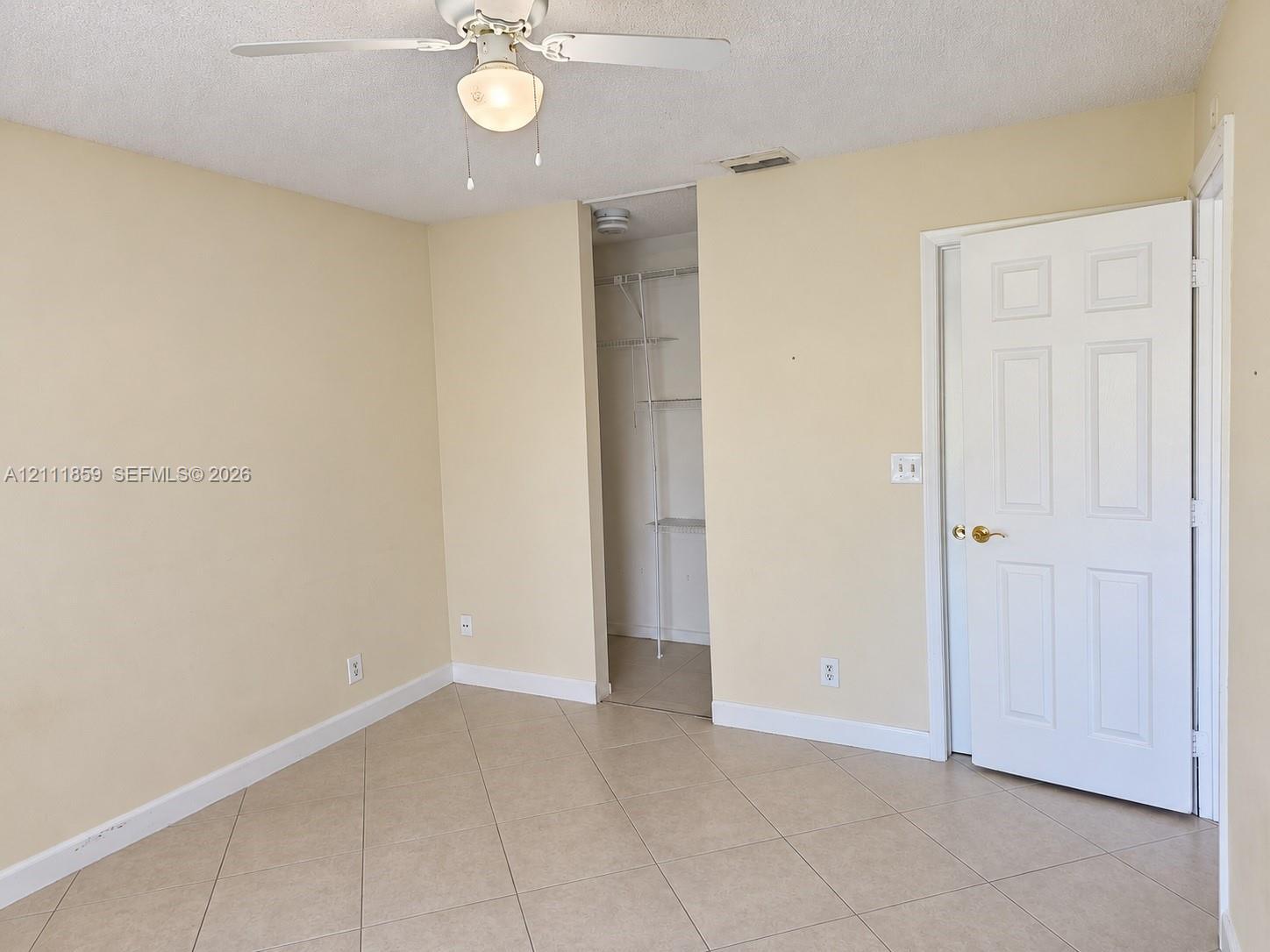 Interior space featuring diagonal tile flooring, a ceiling fan with integrated lighting, and a six-panel door