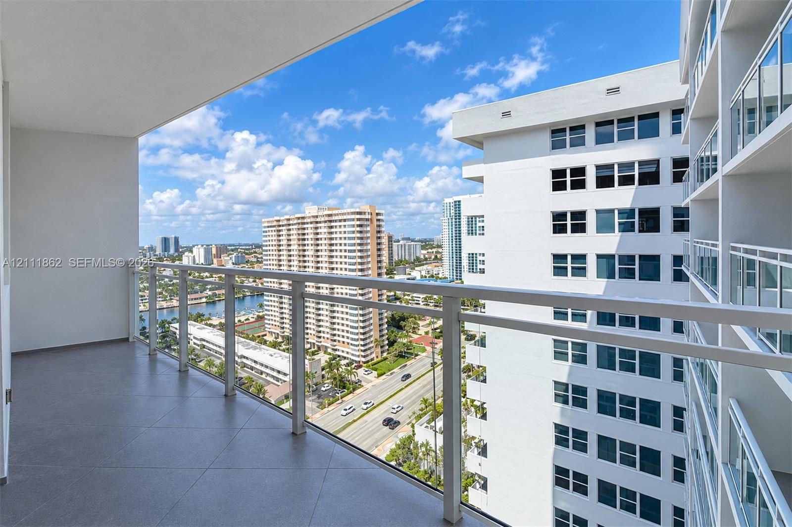 Covered balcony featuring tile flooring and a glass-paneled railing