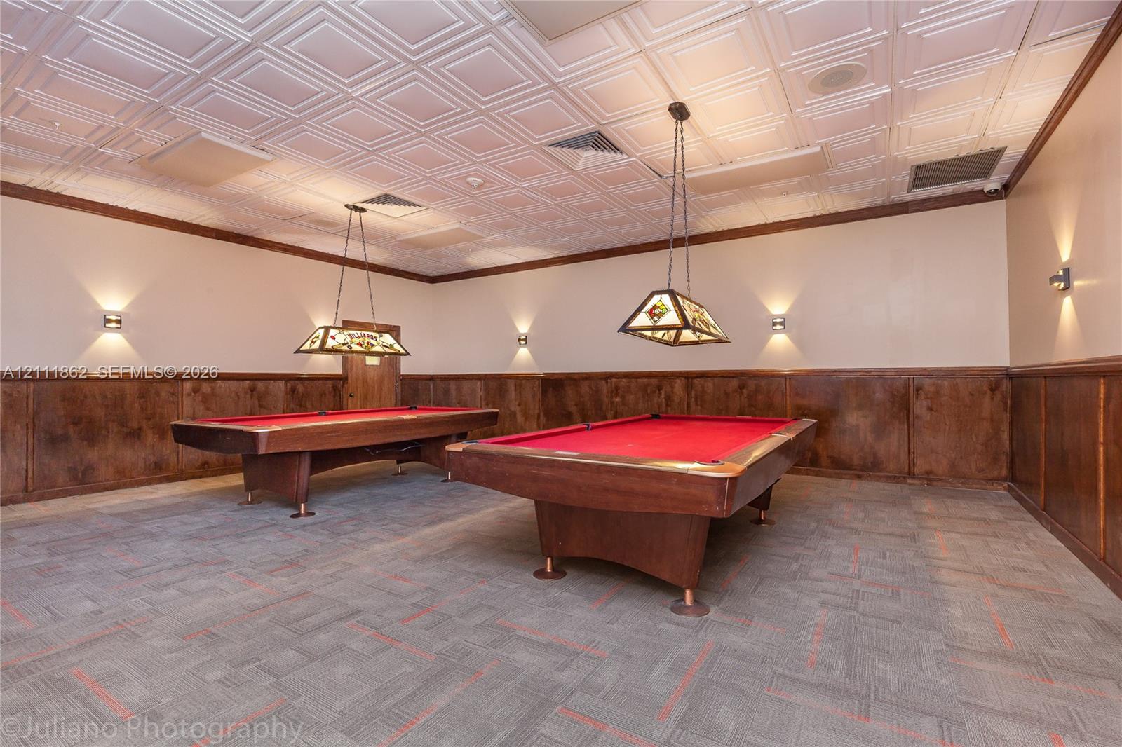 Coffered ceiling tiles, stained wood wainscoting, and decorative stained-glass pendant lighting