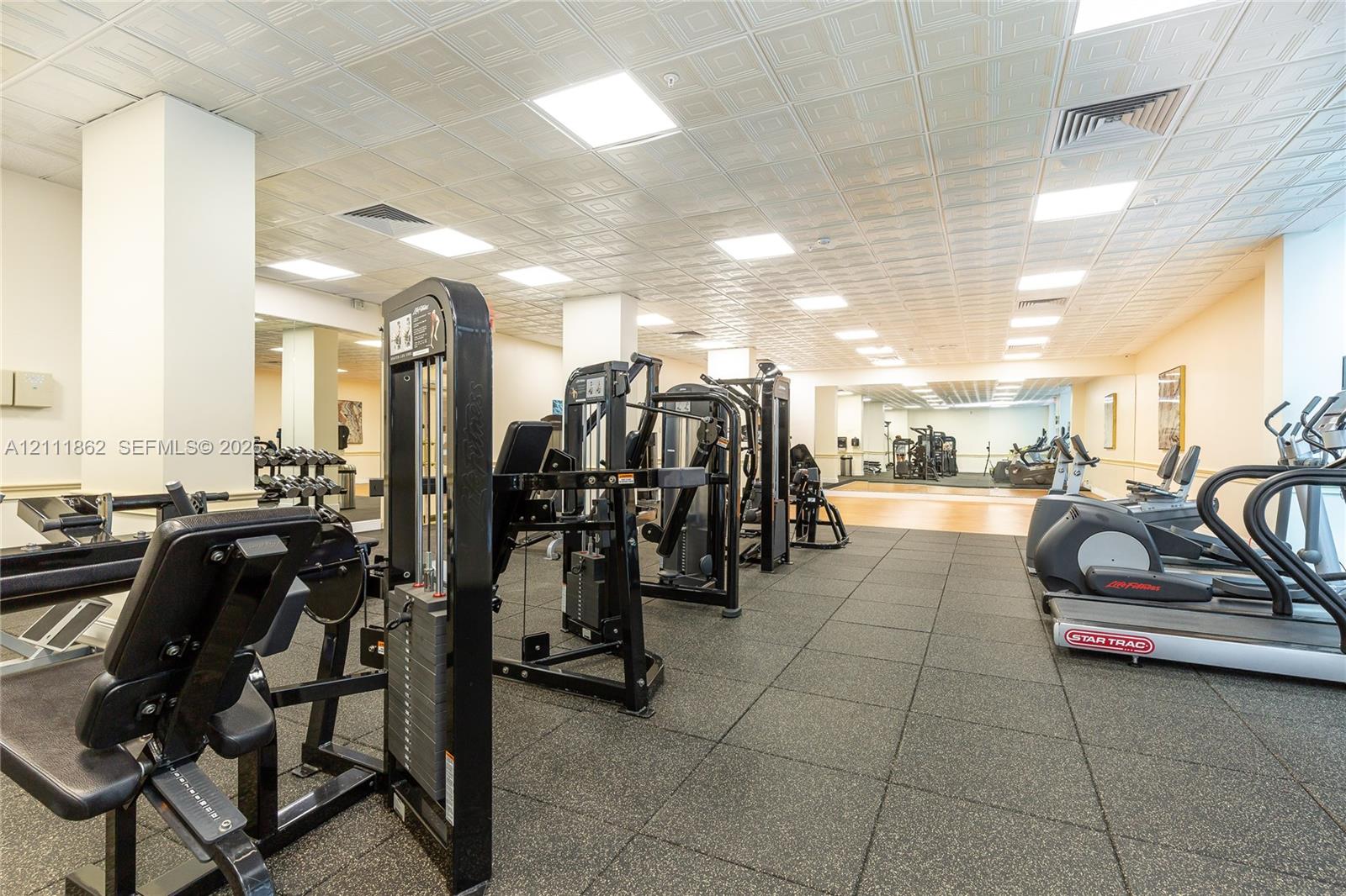 Fitness facility featuring high-contrast rubber flooring, coffered ceiling tiles, and recessed lighting
