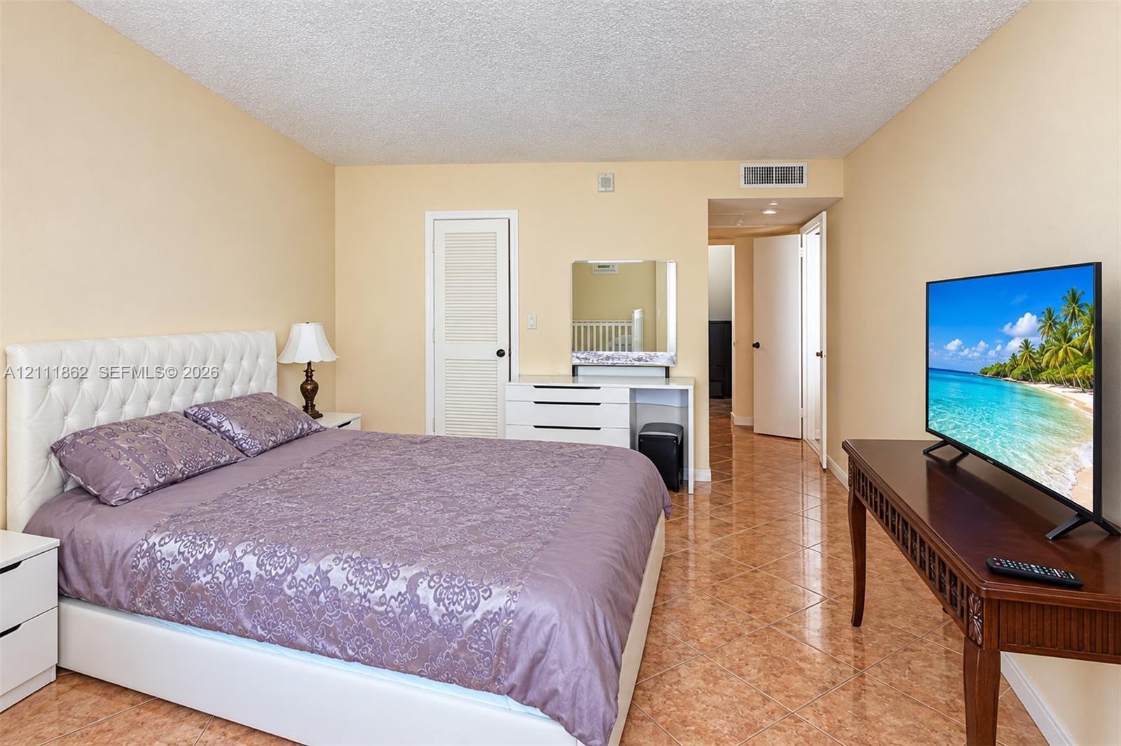 Room featuring polished tile flooring, neutral wall tones, and a built-in louvered-door closet