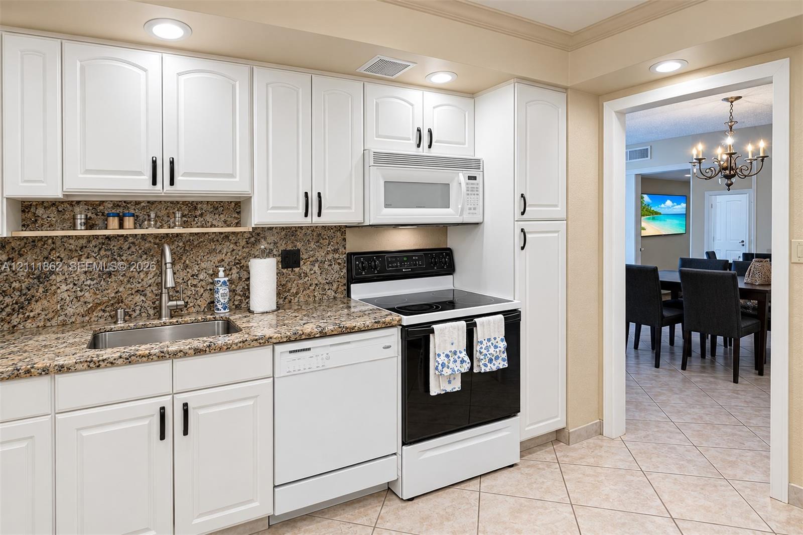 Kitchen featuring white shaker-style cabinetry, stone-finish countertops, stainless steel undermount sink, built-in microwave, and recessed lighting