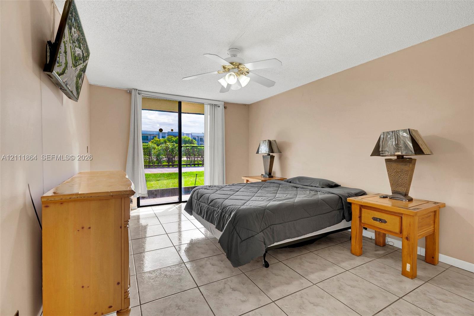 Neutral wall tones, ceramic tile flooring, ceiling fan with light fixture, and sliding glass door with exterior access