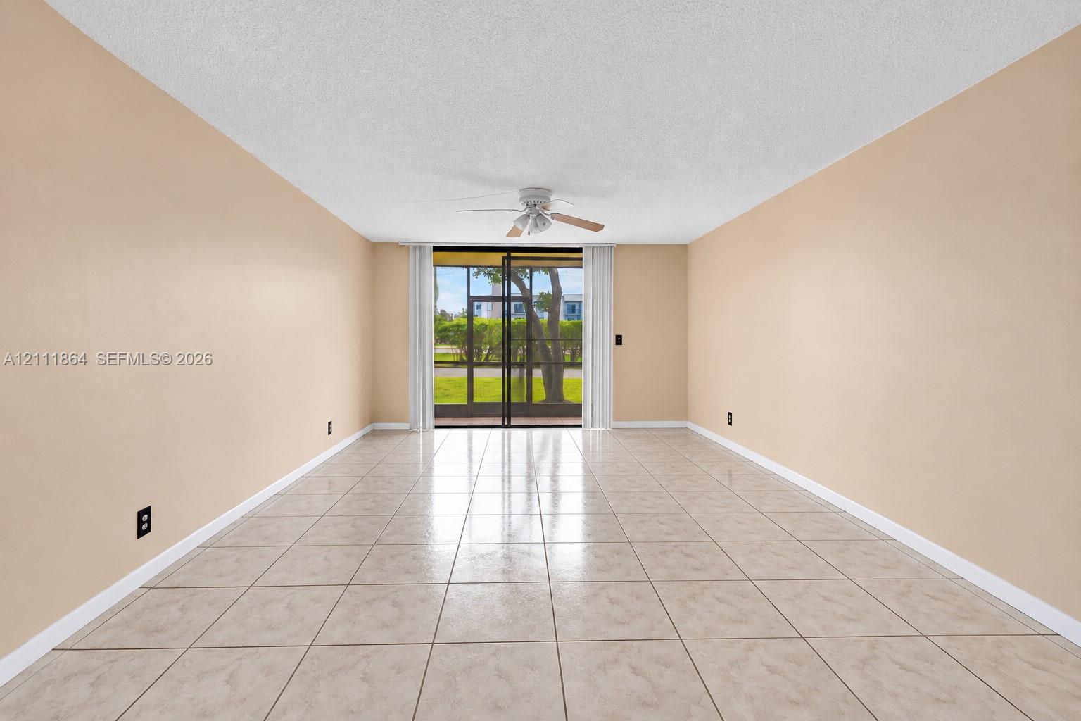Neutral-toned interior featuring ceramic tile flooring, a central ceiling fan, and sliding glass doors