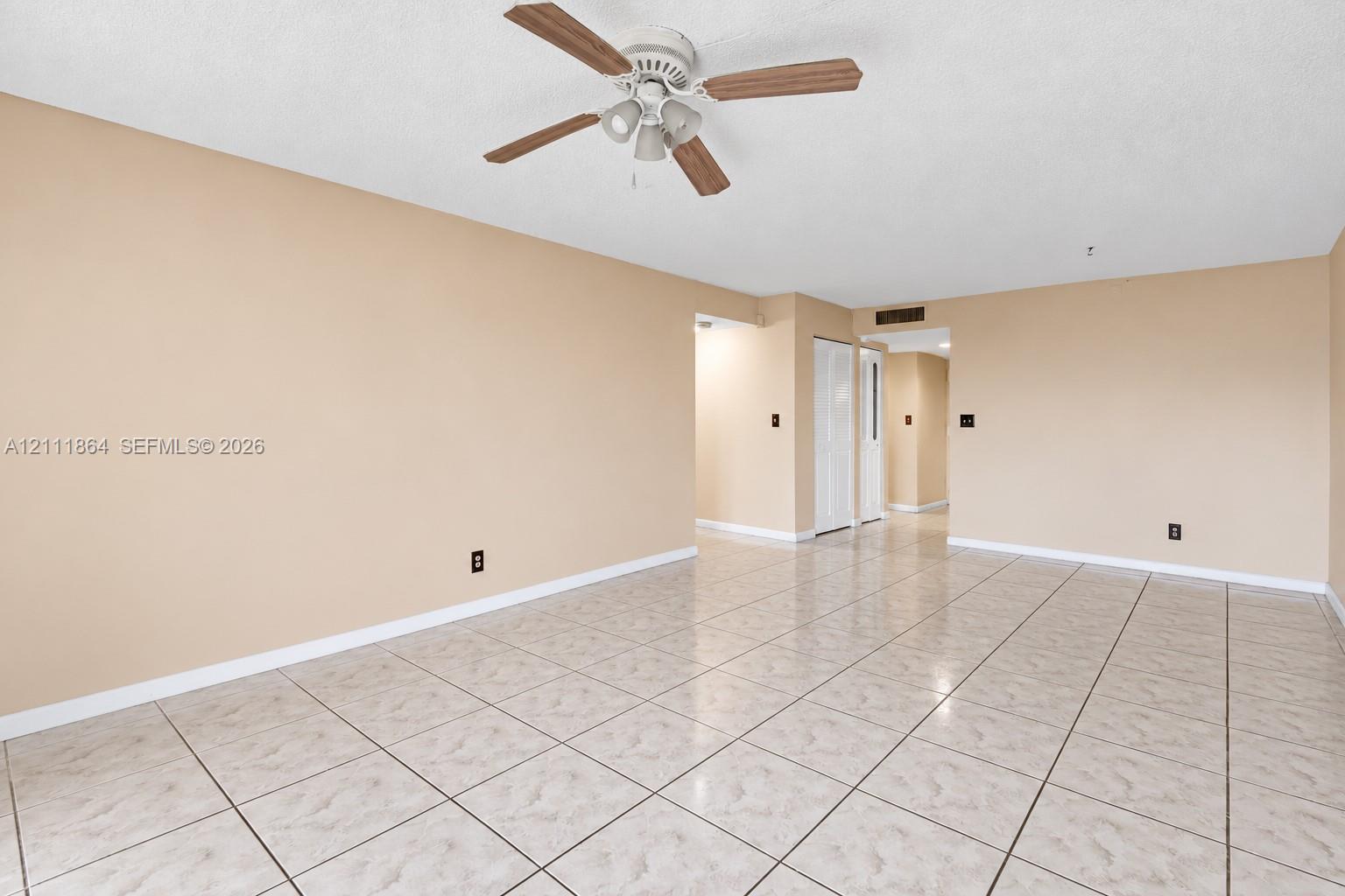 Open interior space featuring neutral wall tones, large-format tile flooring, and a ceiling fan with integrated lighting