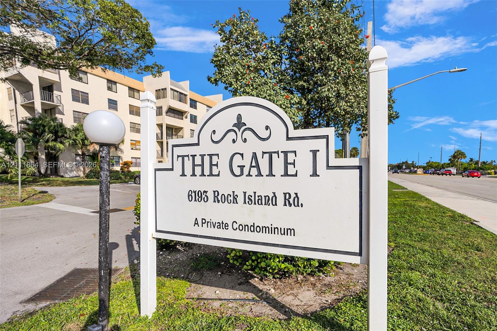 Monument signage for The Gate I condominium featuring an arched, scroll-work design on a post-and-panel frame