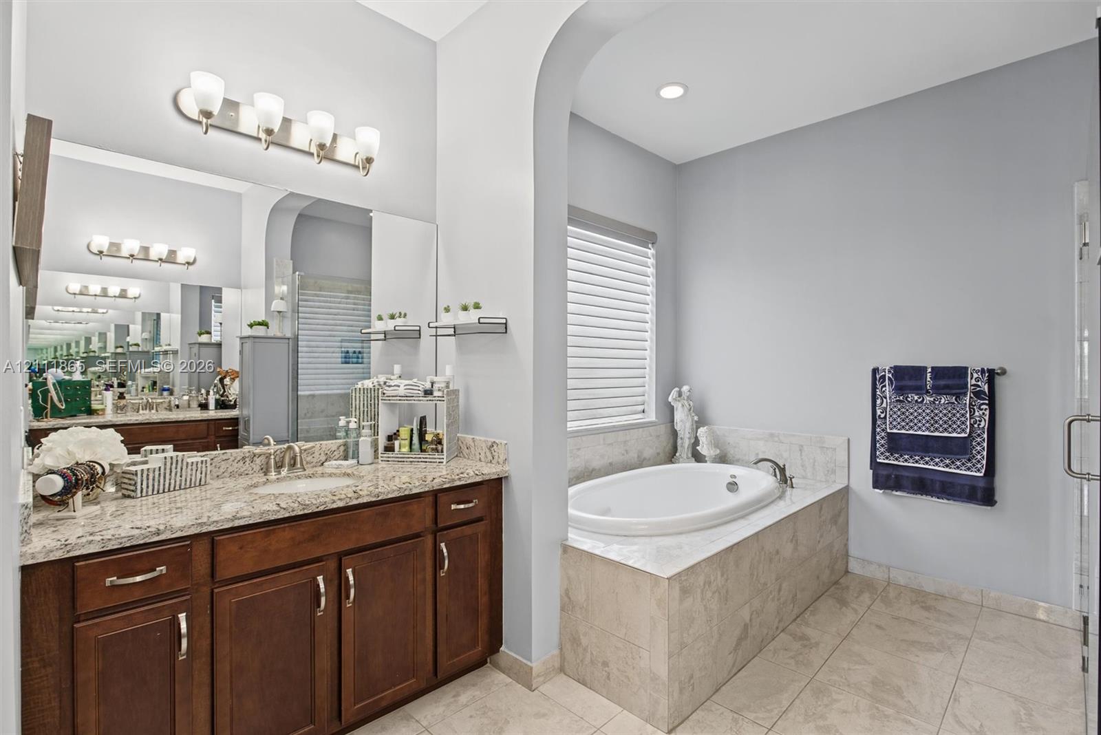 Master Bathroom featuring rich wood cabinetry and stone countertop + soaking tub.