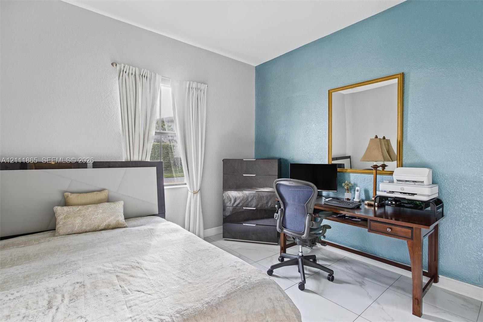Second Bedroom featuring large-format tile flooring, single-pane window, and an accent wall