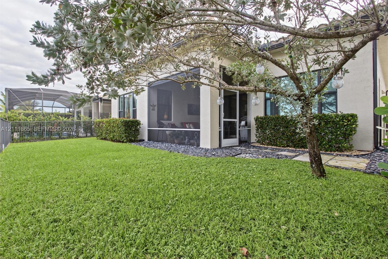 Back yard perspective. Notice lawn, dark stone landscape border, and shade tree