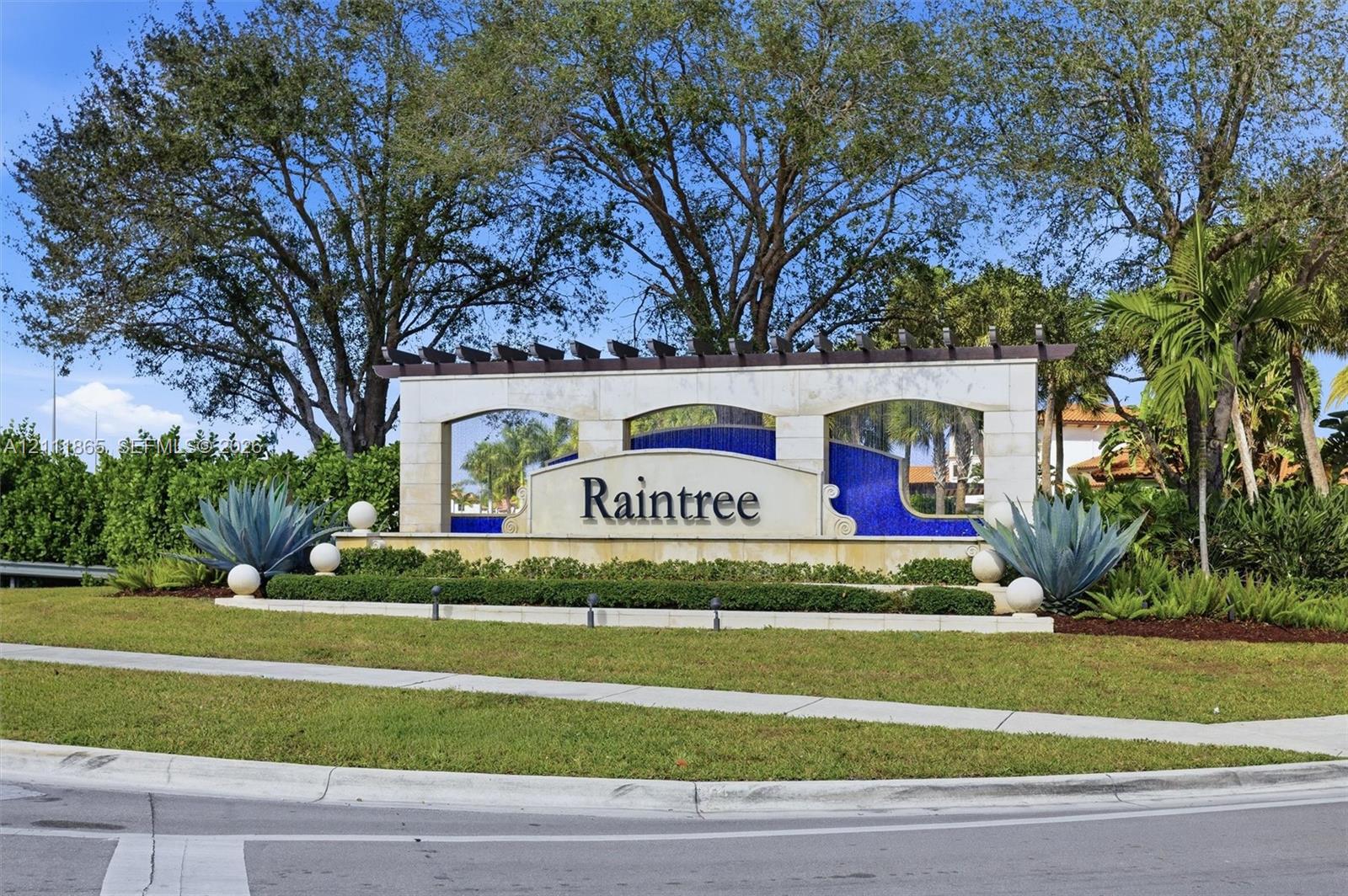 Raintree community entrance monument featuring stone masonry, a decorative wooden pergola, blue tile accents, and professional landscaping