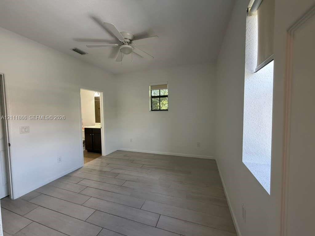 Room featuring wood-finish tile flooring, ceiling fan, and recessed window openings