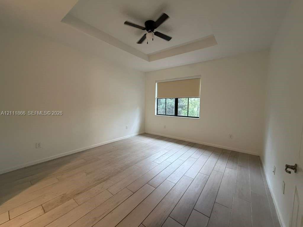 Tray ceiling, wood-finish tile flooring, and integrated ceiling fan