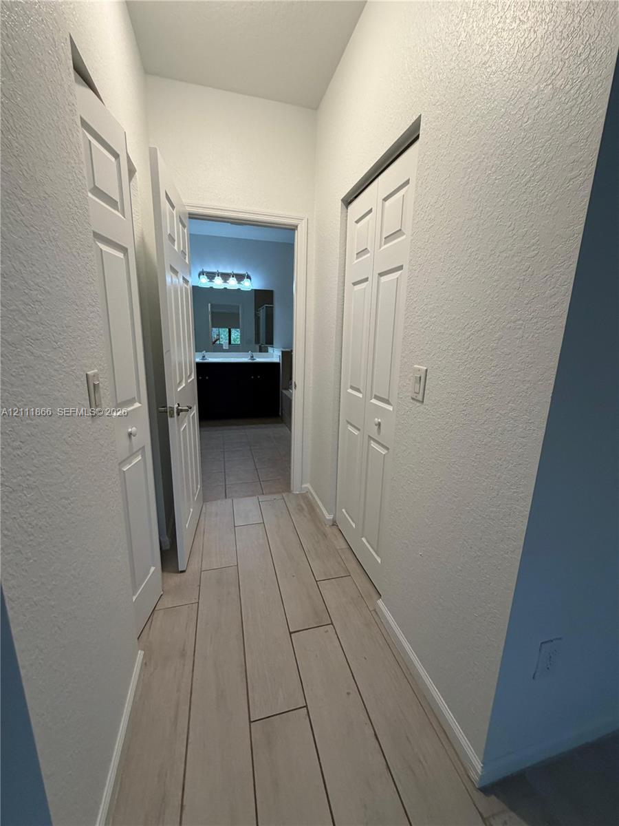 Hallway featuring wood-finish tile flooring and dual-panel closet doors