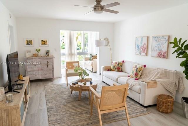 Living area featuring neutral wall paint, wood-finish flooring, and a ceiling-mounted fan with integrated lighting Living area featuring neutral wall paint, wood-finish flooring, and a ceiling-mounted fan with integrated lighting