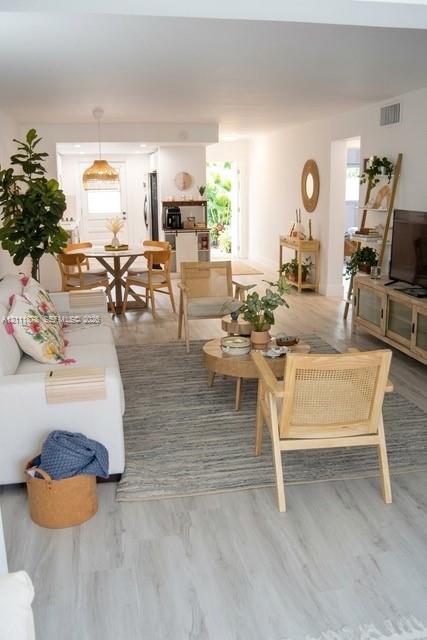 Open-concept interior featuring wood-finish flooring, neutral walls, and a recessed ceiling lighting fixture Open-concept interior featuring wood-finish flooring, neutral walls, and a recessed ceiling lighting fixture